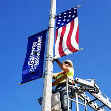 Technician installing a municipal street banner from a lift